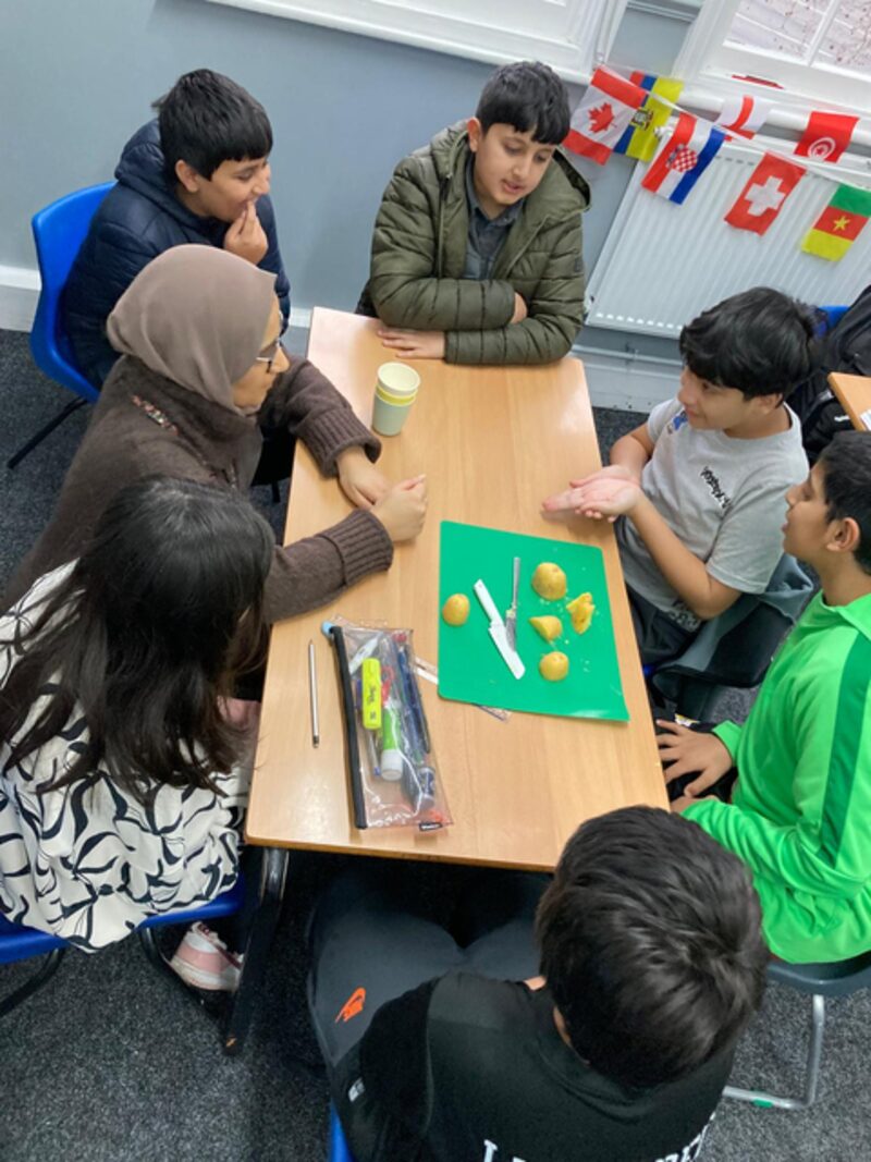 Miss Jenna, Science teacher, with students at a work table